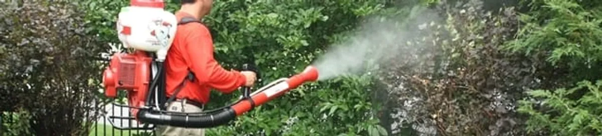 Mosquito control technician fogging shrubs and landscaping for mosquito treatment in Bradenton, FL