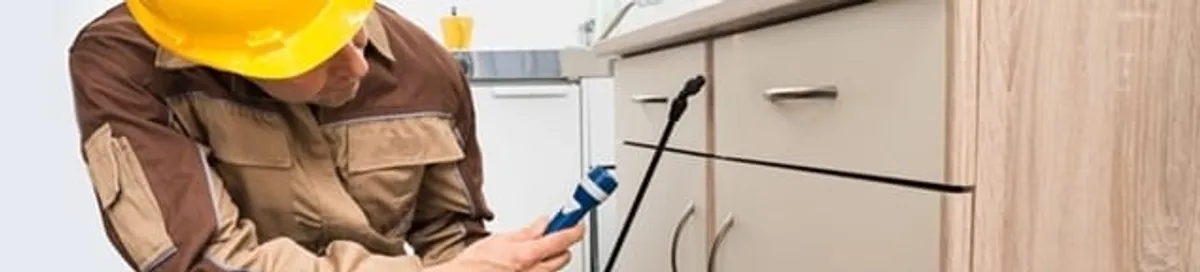 Roach exterminator applying treatment under kitchen cabinets in Bradenton, FL